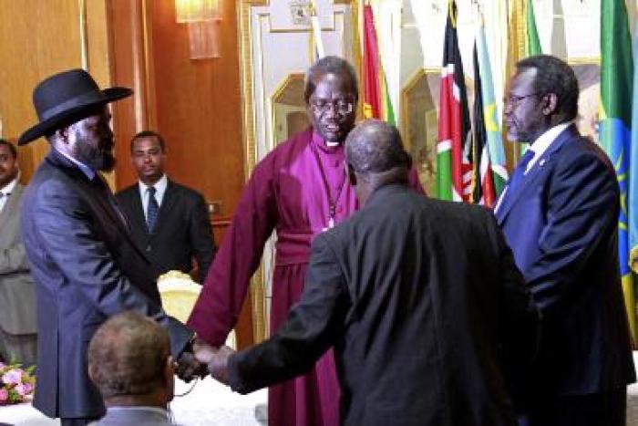 South Sudan’s president, Salva Kiir (L), and rebel leader Riek Machar (R) shake hands and pray before signing a ceasefire agreement aimed at ending conflict in the country in the Ethiopian capital, Addis Ababa, on 9 May 2014 (Photo: AP/Elias Asmare)